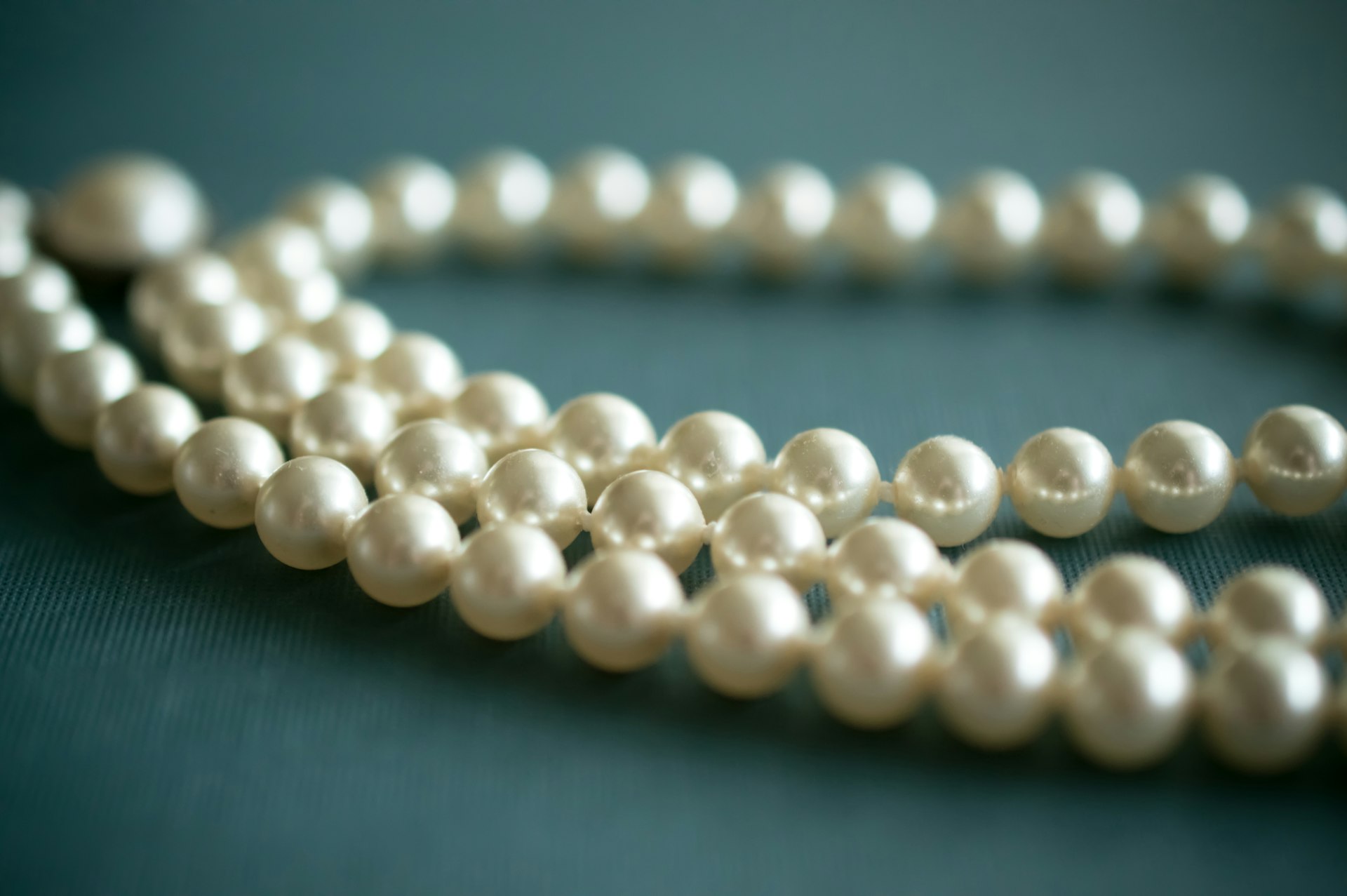white pearl necklace on gray textile